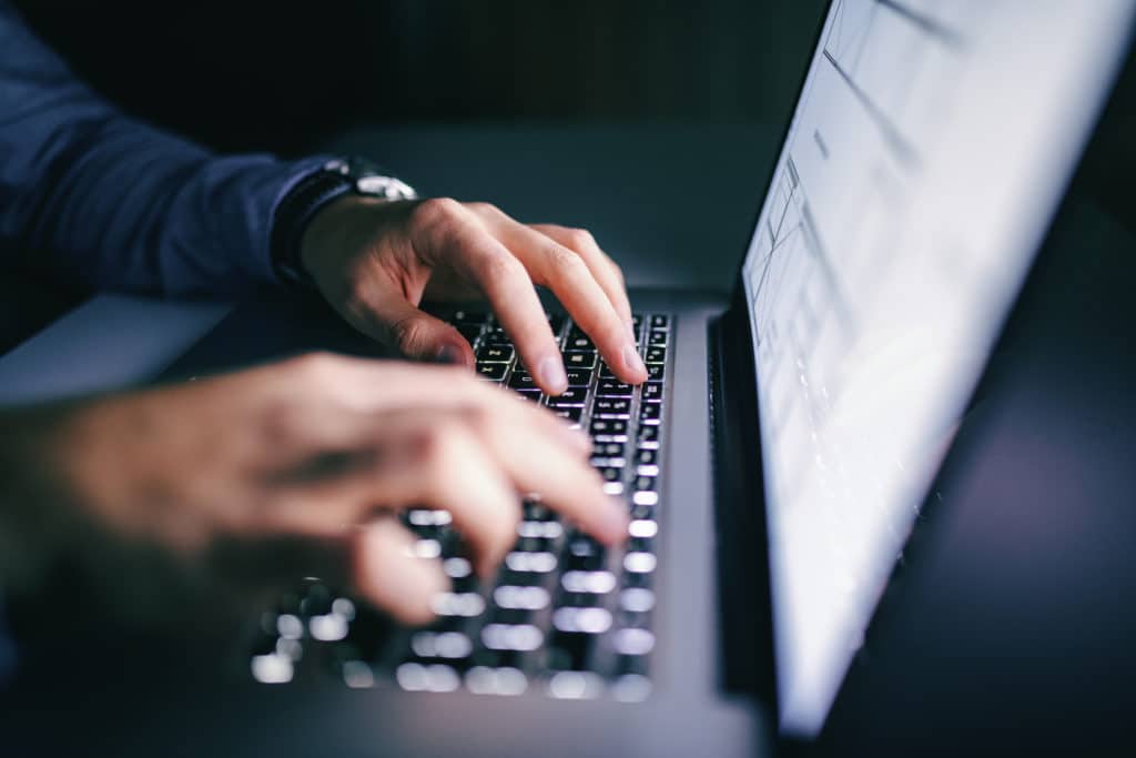 Close up of hands typing on laptop.