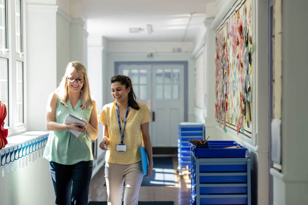 Trust staff members discussing invoice management whilst walking together through a school hall.