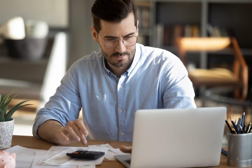 Man with laptop and calculator reading about making tax digital (MTD)