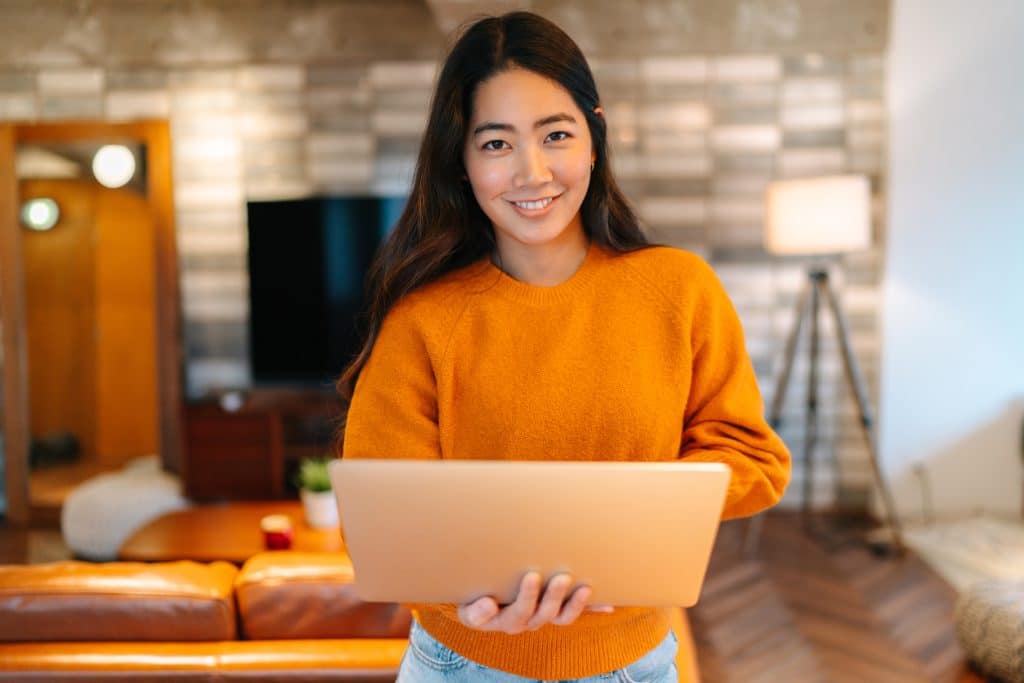 Woman in orange jumper holding laptop