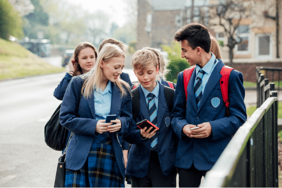 school children using mobile phones on their way to school
