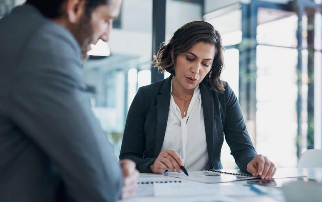 Business man, woman and paperwork with discussion for deal, agreement and proposal for b2b collaboration. People, staff and meeting with documents for financial strategy, stats and feedback in office