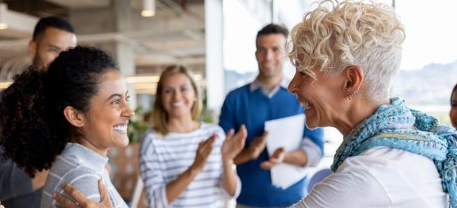 As people applaud, a boss is giving a staff member a promotion.